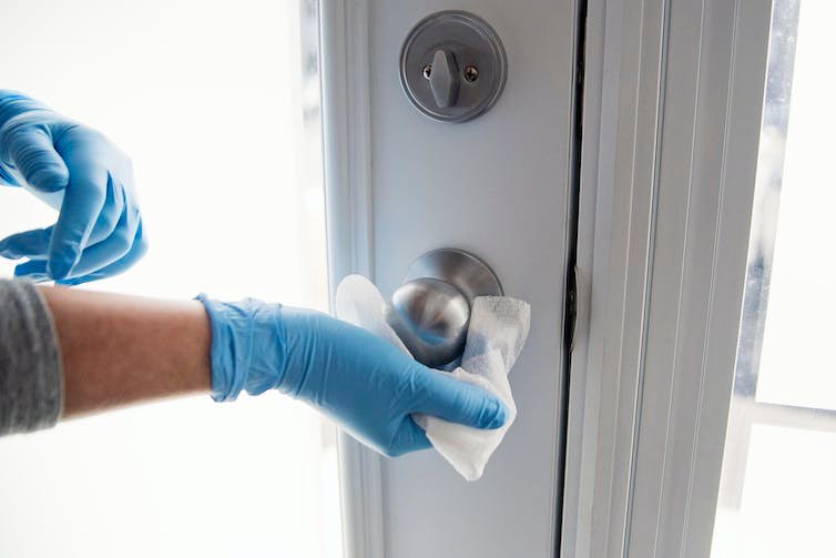 दस्‍ताने वाले हाथ दरवाज़े की कुंडी पोंछते हुए